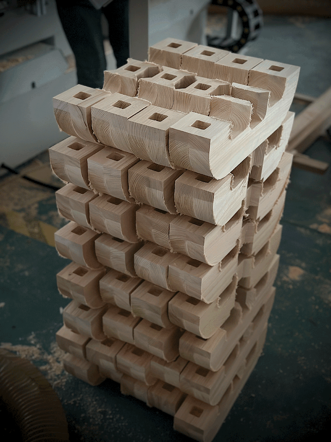 Stacked shaped wooden blocks with square joinery openings and visible cut grain