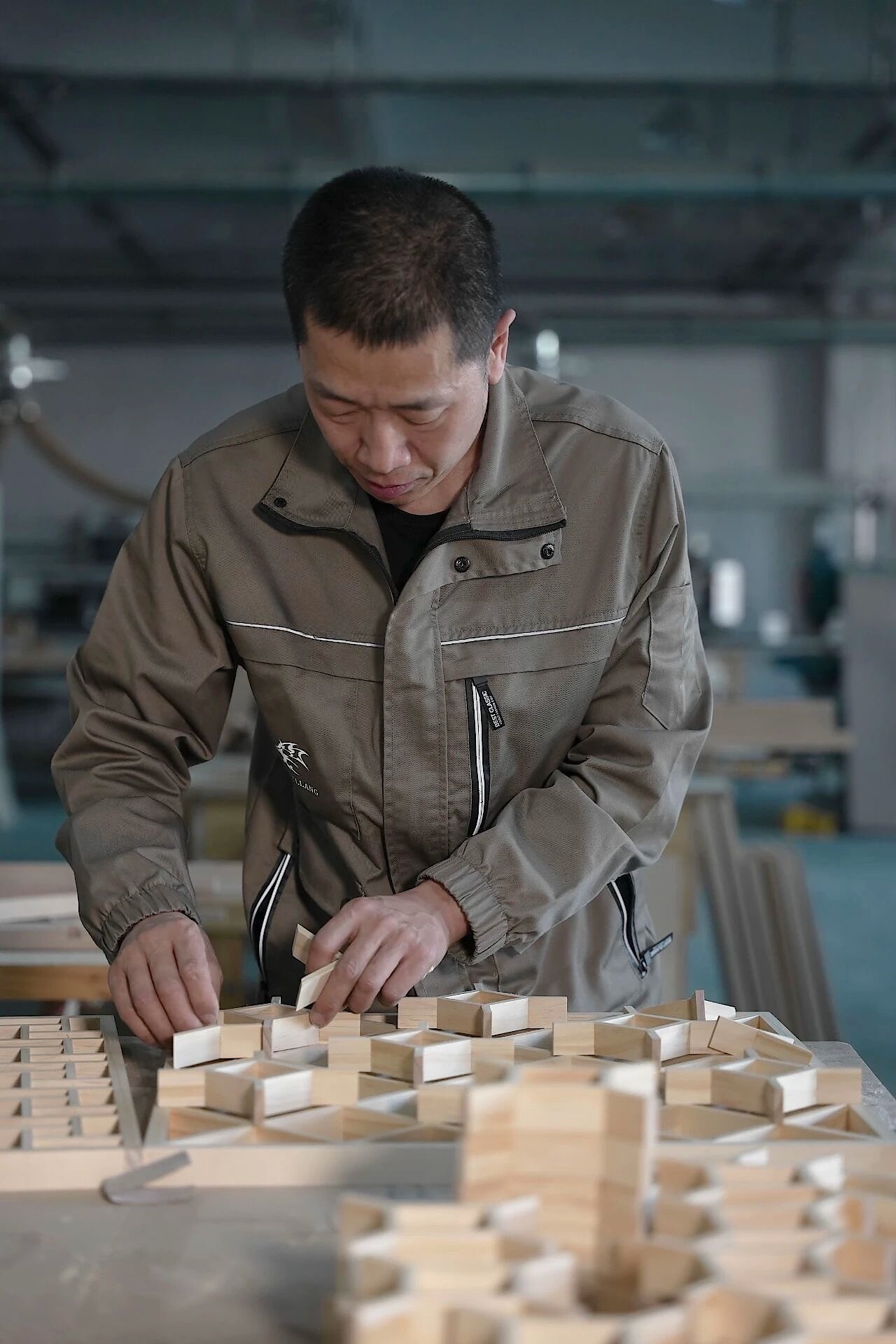 Worker positioning small wooden pieces in a geometric arrangement on a workbench