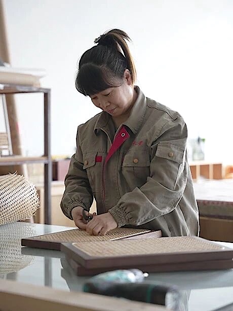 Worker securing a light woven panel within a dark wooden frame