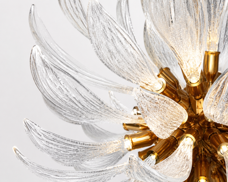 Close-up of textured clear glass leaves surrounding golden-toned chandelier fittings