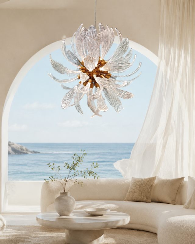 Round glass-leaf chandelier above an ivory sofa overlooking the sea through a wide arch