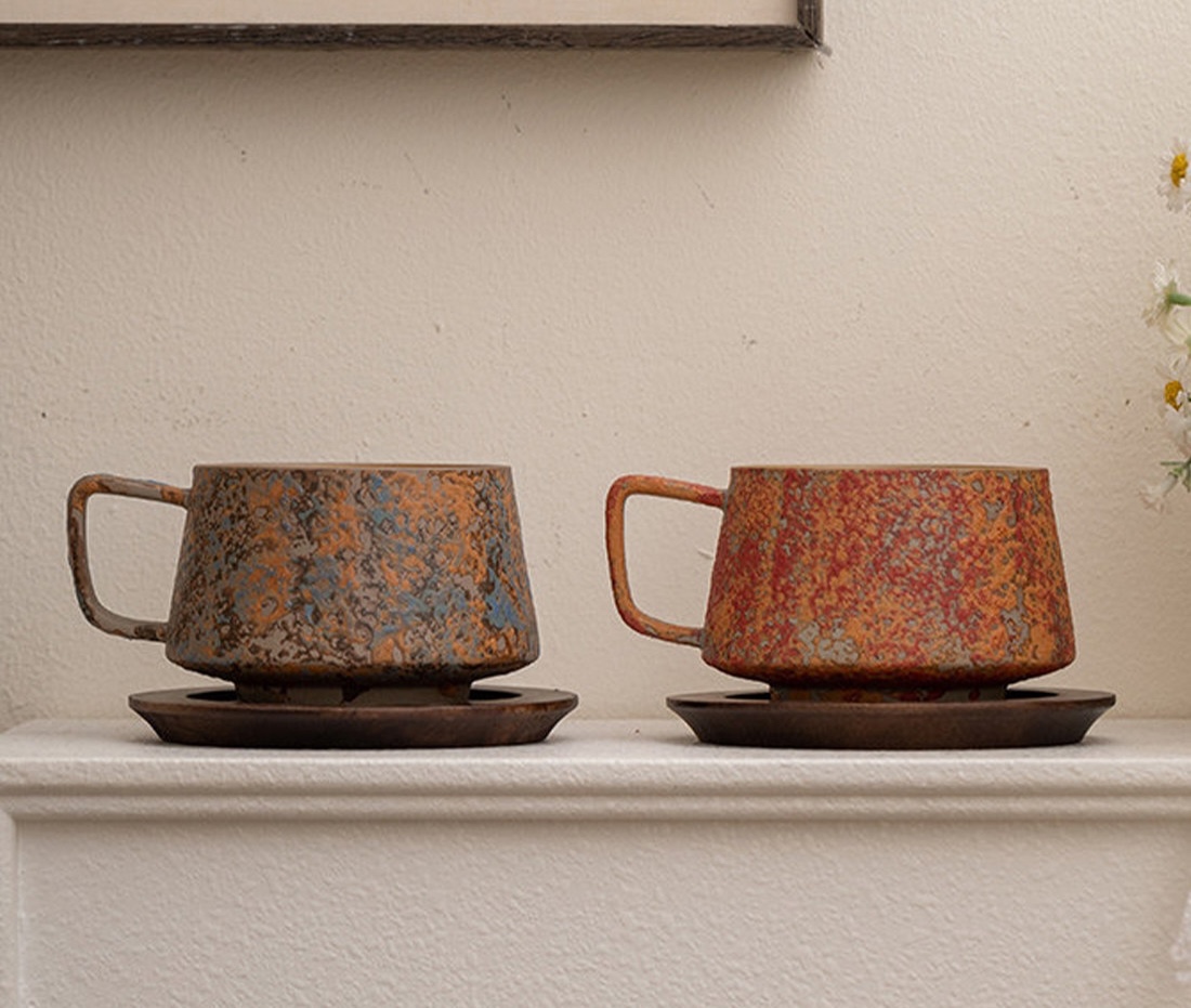 Blue-grey and red mottled cups on dark wooden saucers on a shelf