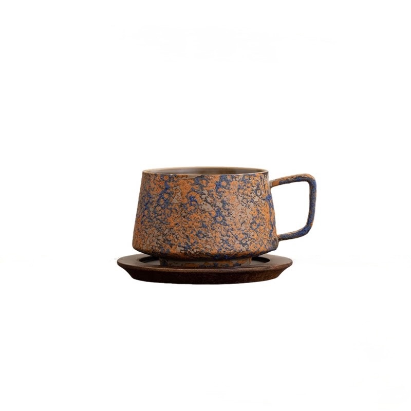 Rust Yellow cup with ochre and dark blue speckles on a wooden saucer