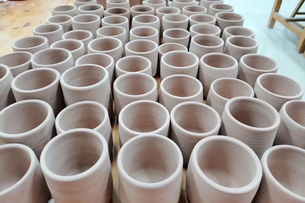 Rows of unfinished clay cups on a workshop table