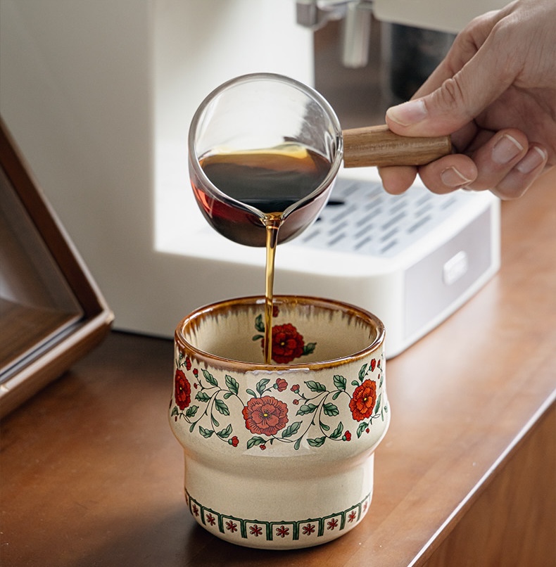 Coffee poured from a glass server into a Crimson Blossom cup