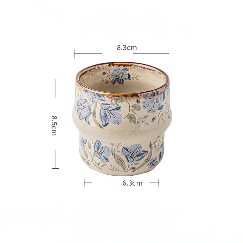 Blue Botanica cup with blue flowers and green leaves on a cream background