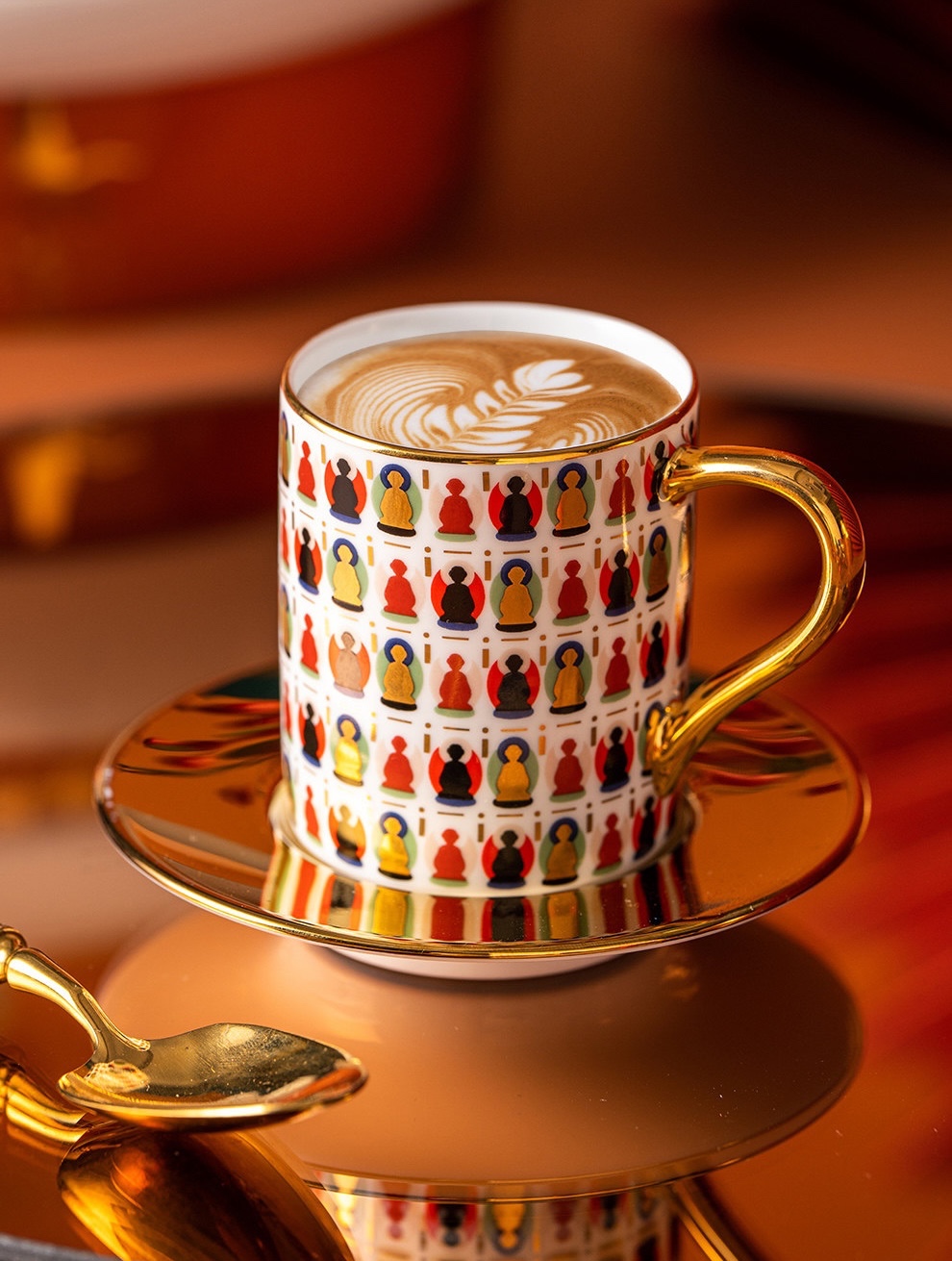 Ivory Dunhuang cup filled with coffee and latte art on a reflective gold-tone saucer