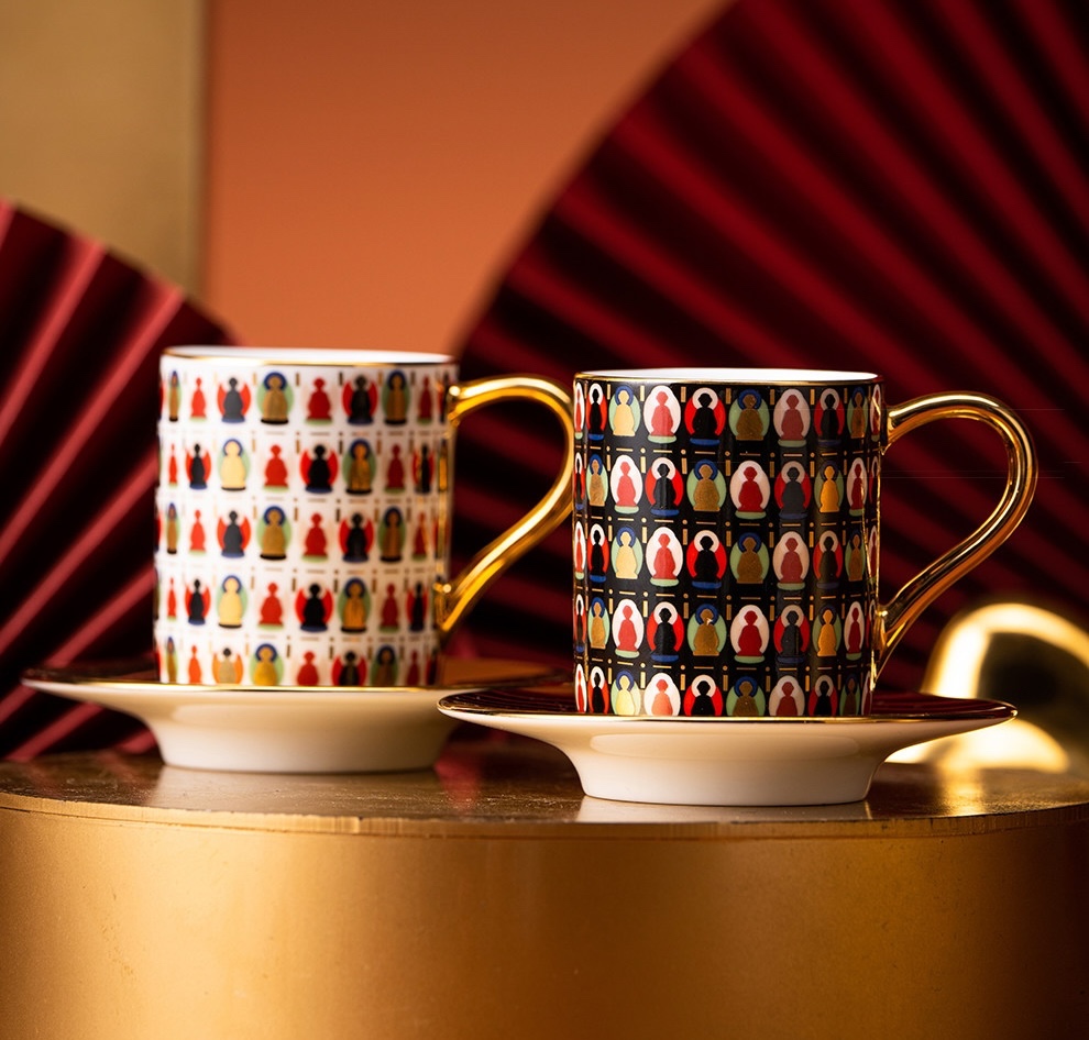Ivory and onyx Dunhuang cups on saucers with gold-tone surfaces against folded red fans