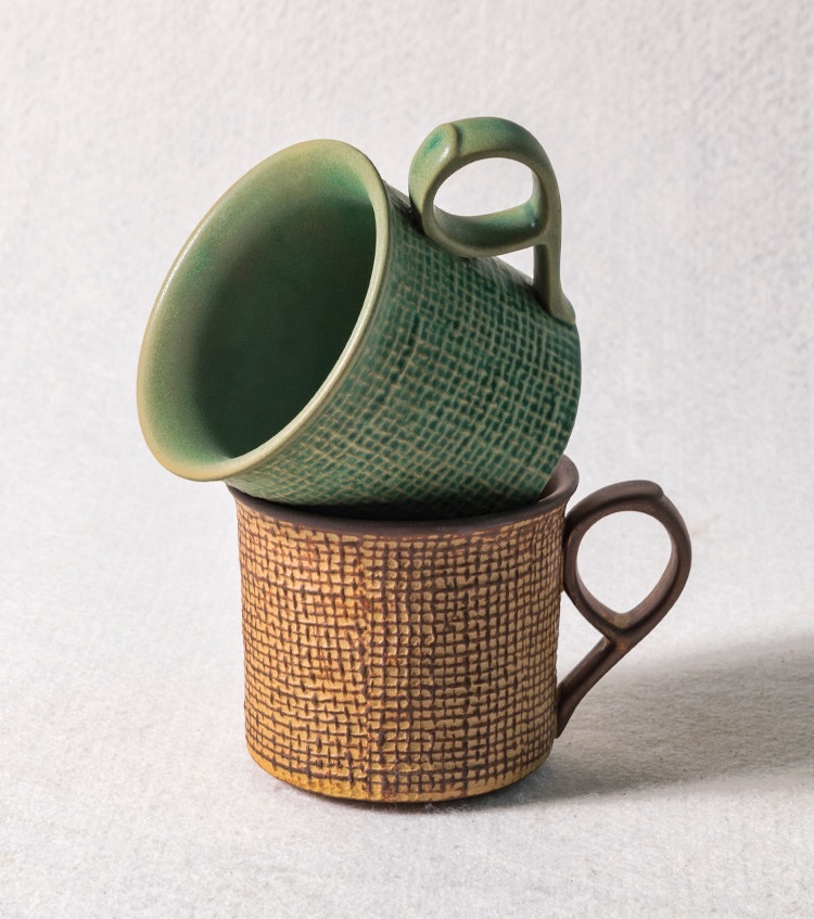 Stacked green and amber cups showing smooth interiors and loop handles