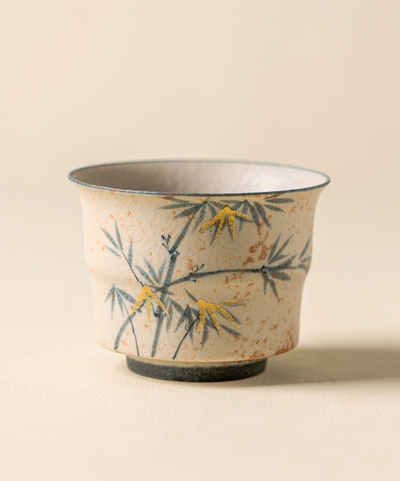 Cream tea cup with blue-grey bamboo, gold-coloured accents and a dark foot ring