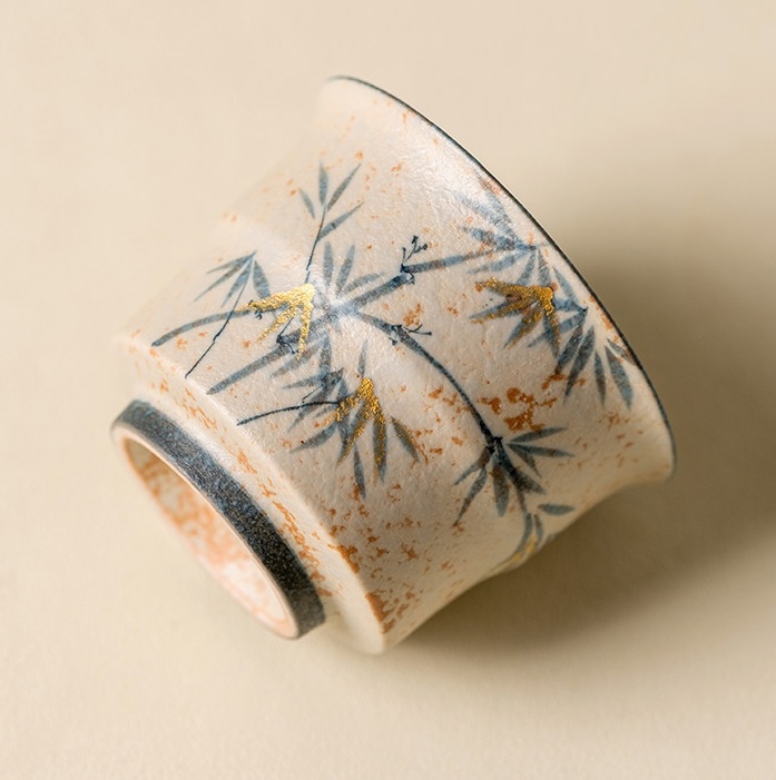 Close-up of bamboo decoration and gold-coloured accents on the speckled cream cup