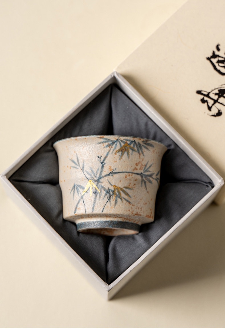 Decorated cream tea cup nestled in a dark fabric-lined presentation box
